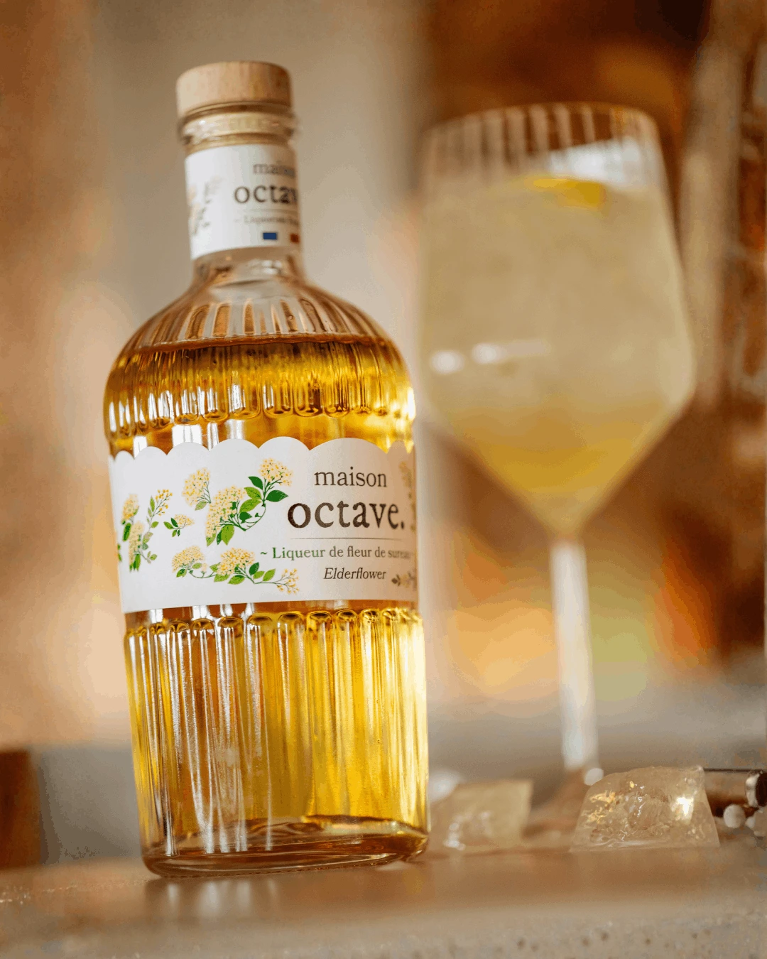 Bouteille Maison Octave et verre glacé, gros plan sur l'étiquette fleur de sureau
